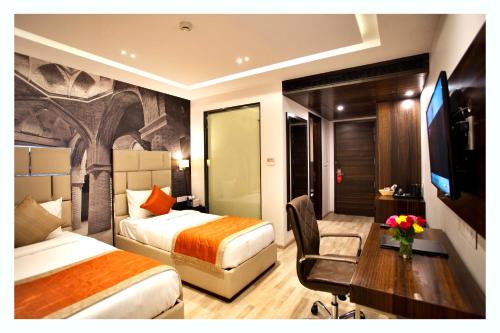 a hotel room with two beds and a desk and a tv at Kaisons Inn (Near Apollo Hospital) in New Delhi