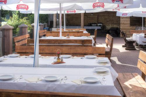 a group of tables with white plates and an umbrella at Panoramic-Oscar in Mrągowo