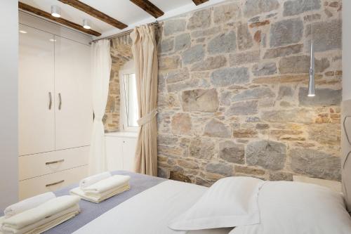 1 dormitorio con pared de piedra y 1 cama con toallas en Split Inn Apartments, en Split