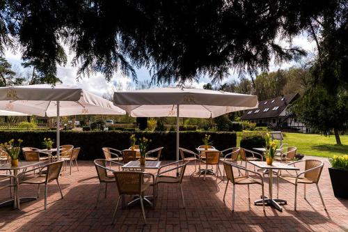 a group of tables and chairs with white umbrellas at Landhotel Cafe Prälank in Neustrelitz