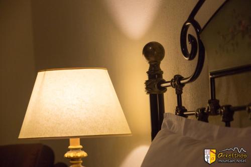 a lamp that is next to a bed at Arkefthos Mountain Hotel in Papigko