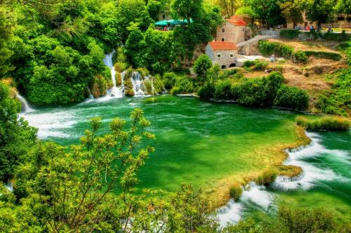 a waterfall and a river with green water at Hotel Skradinski Buk in Skradin