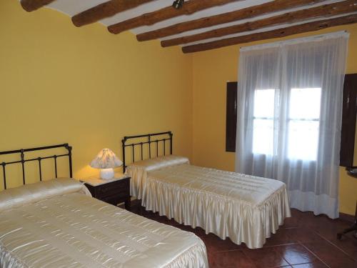 two beds in a room with a window at Las Bodegas Del Gilo in Valdealgorfa