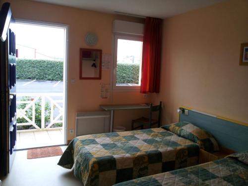 a hotel room with two beds and a window at Tour Hôtel in Lesparre-Médoc