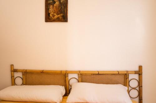 a bed with two pillows and a painting on the wall at Il Mare In Giardino in Scauri