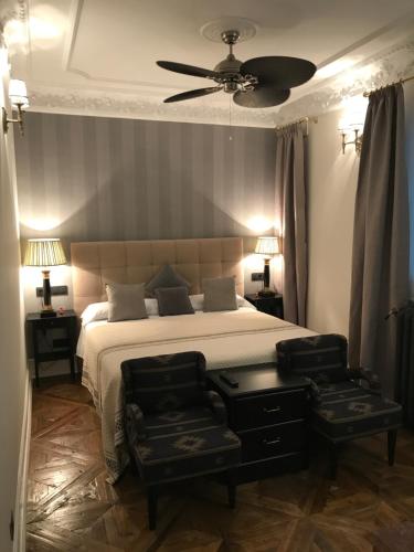 Apartment Suite Carranza في مدريد: غرفة نوم بسرير مع كرسيين ومروحة سقف