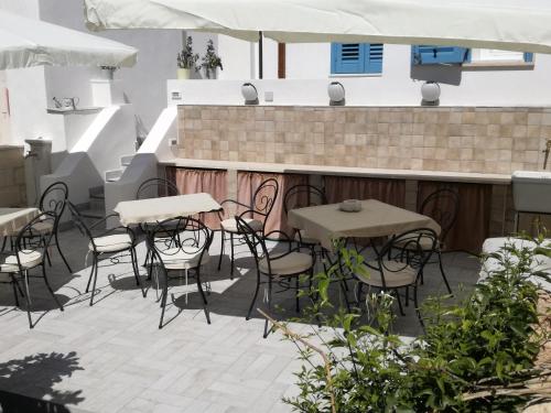 a patio with tables and chairs and a bar at Poggiamico Guest House in Favignana