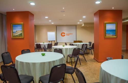 a conference room with tables and chairs and a screen at Comodoro Hotel in Comodoro Rivadavia