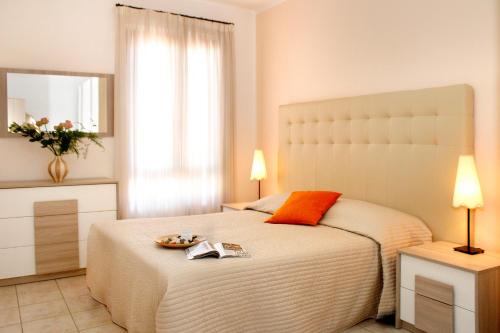 a bedroom with a large white bed and a mirror at Residence Teclini in Castiglione della Pescaia