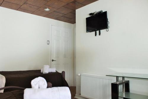 a room with a couch and a tv on the wall at Hotel HF in Farellones