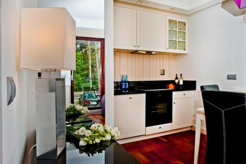 a kitchen with white cabinets and a black refrigerator at Villa Aqua BlueApart Jurata in Jurata