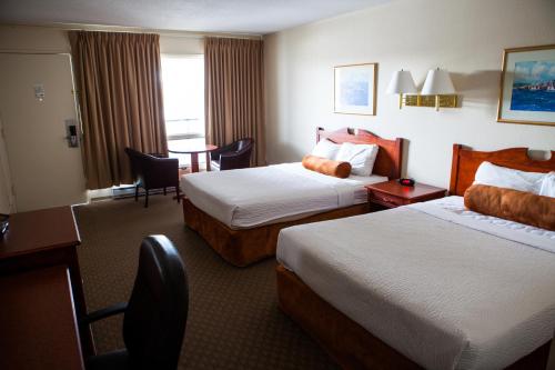 a hotel room with two beds and a table at Knights Inn Lethbridge in Lethbridge