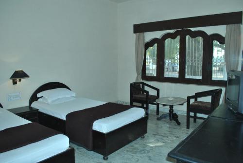 a bedroom with two beds and a table and chairs at Hotel Marble Palace in Khajurāho