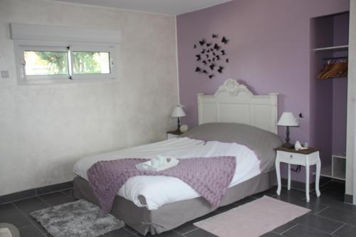 a bedroom with a large bed with purple walls at Comme un Rêve in Doignies