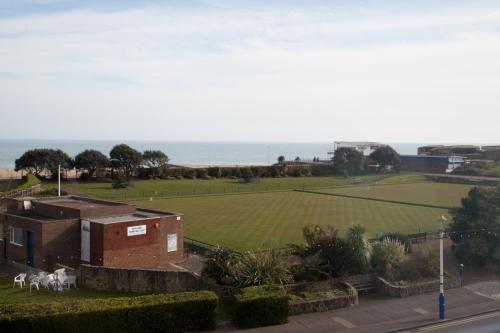 a view of a field with a building and animals at The Langtons in Eastbourne