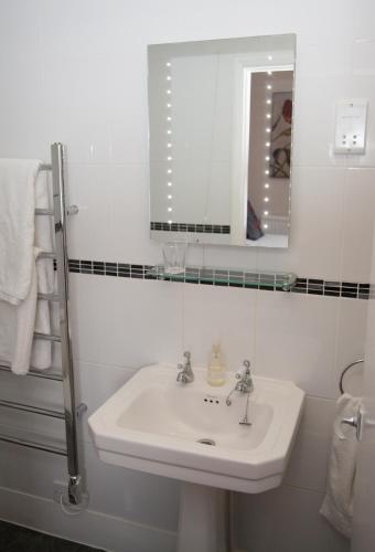 a white bathroom with a sink and a mirror at The Langtons in Eastbourne