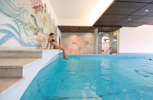 a woman sitting on the edge of a swimming pool at Parkhotel Wallgau in Wallgau