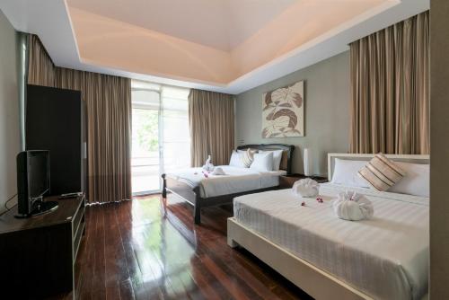 Una habitación de hotel con dos camas y un televisor. en Tropical Garden Paradise Villa, en Na Jomtien
