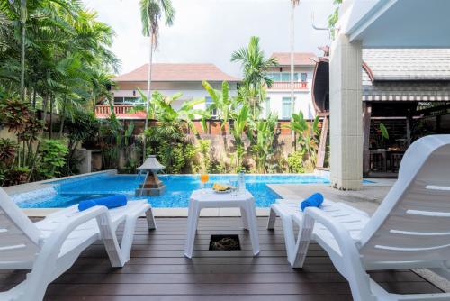 a patio with chairs and a table next to a swimming pool at Tropical Garden Paradise Villa in Na Jomtien