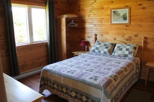 een slaapkamer met een bed in een blokhut bij Swept Away Cottages in Cavendish
