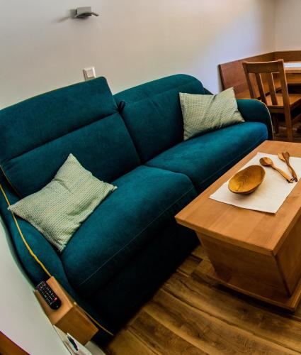 a blue couch sitting next to a wooden table at Apartments BBI in Luče