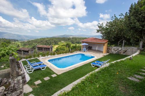 a swimming pool in a yard with two blue chairs at Casa De Santo Andre in Monção