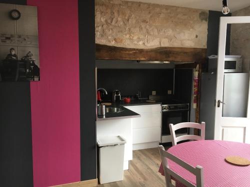 une cuisine avec une table et un mur rose dans l'établissement L'ANNEXE, à Carennac
