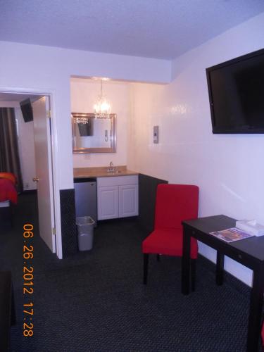 a hotel room with a red chair and a table at Tradewinds Airport Hotel in Inglewood