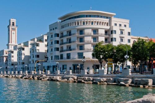 un grand bâtiment blanc à côté d'une étendue d'eau dans l'établissement JR Hotels Bari Grande Albergo delle Nazioni, à Bari