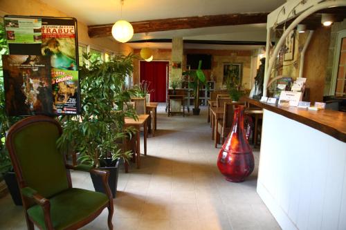 ein Restaurant mit Tischen und Stühlen und eine Bar mit Pflanzen in der Unterkunft Apart'Hôtel Les 4 Sources in Anduze