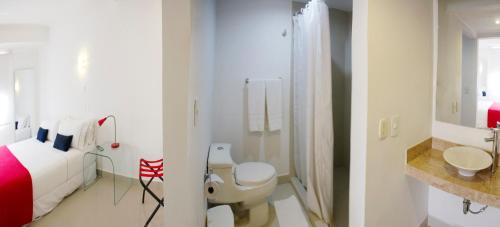 baño blanco con cama y ducha en Zalmedina Hotel, en Cartagena de Indias
