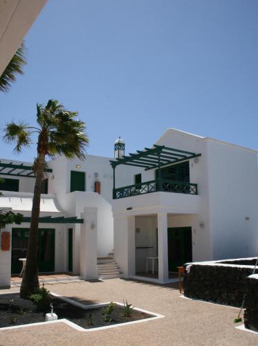 a white building with a palm tree in front of it at Apartamentos las Acacias in Puerto del Carmen