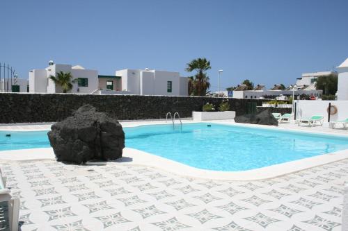 a swimming pool with a rock in the middle at Apartamentos las Acacias in Puerto del Carmen