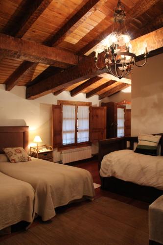 a bedroom with two beds and a ceiling with beams at Mañuko Benta in Bermeo