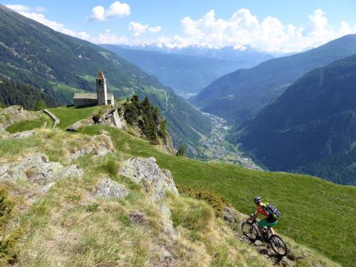 a person riding a bike on a hill overlooking a valley at Rifugio Alpe San Romerio in Brusio