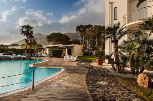 a swimming pool with a wooden walkway next to a house at Hotel Orsa Maggiore in Vulcano