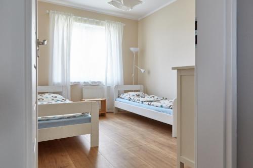 due letti in una piccola stanza con una finestra di Sunrise Apartamenty a Łeba
