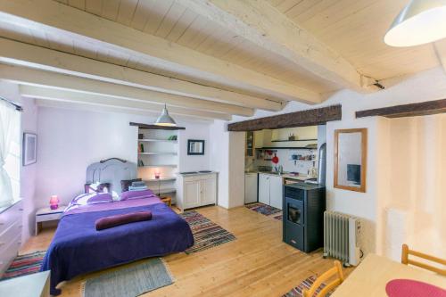 a bedroom with a purple bed and a kitchen at Apartments Galerija Motovun in Motovun