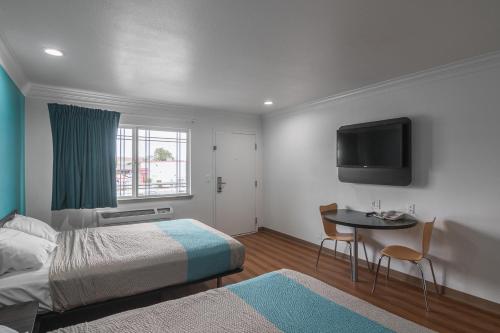 a bedroom with a bed and a table and a tv at Motel 6-Norwalk, CA in Norwalk