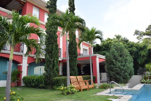 a pink house with palm trees and a swimming pool at Altos de Fontana in Managua