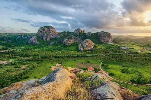 a group of large rocks on a green field at Pousada Vale Encantado in Serra de São Bento