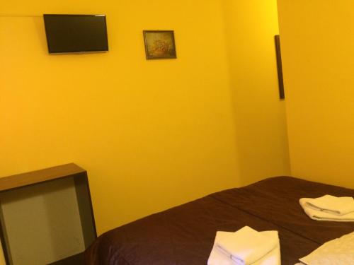 een gele kamer met een bed en een televisie bij Hotel Travel in Lviv