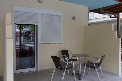 un patio con sillas, una mesa y una ventana en Filia Apartments, en Olympiakí Aktí