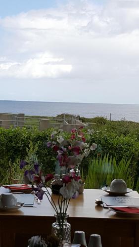 a table with flowers on it with the ocean in the background at Ocean Heights B&B in Lissadell