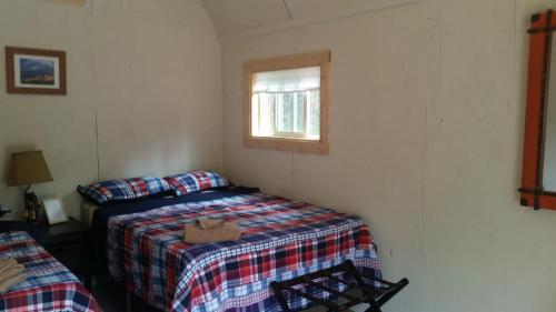 a small bedroom with a bed and a window at DFA Cabin Rentals in Talkeetna