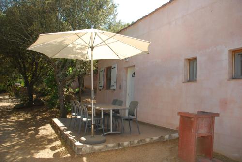 a table with chairs and an umbrella next to a building at Residence Ribellinu in Pianottoli-Caldarello