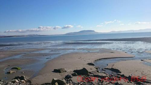 a beach with rocks and water and mountains in the background at Ocean Heights B&B in Lissadell