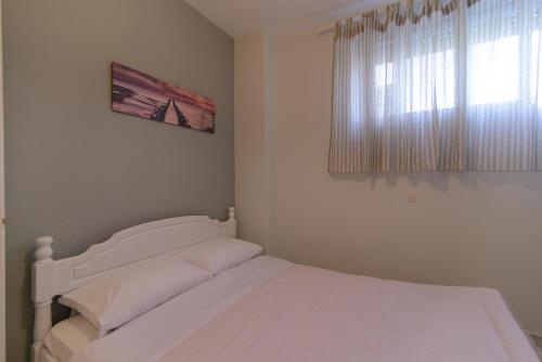 a white bed in a bedroom with a window at Family Inn Apartments&suites in Neos Marmaras