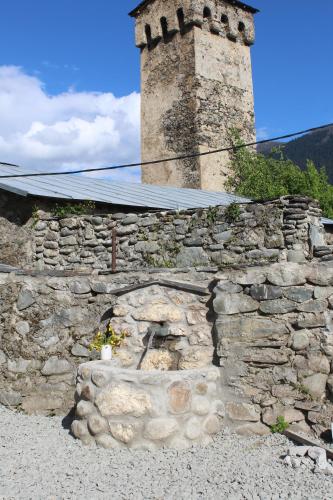 a stone wall with a fireplace in front of a tower at Bapsha Guesthouse in Mestia