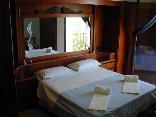 a bedroom with a large white bed with a mirror at Hotel Vittorio in Portopalo
